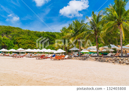 luxury resort with sun beds and umbrellas under palm trees on beach by the sea in summer. Landscape with view of shore coast by the ocean. Tropical island beach. Travel vacation destination in Asia 132403808
