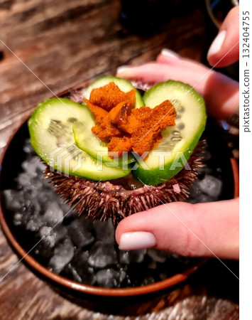 Gourmet Sea Urchin Roe (Uni) Served on Sliced Cucumber Inside a Sea Urchin Shell with Crushed Ice. 132404755