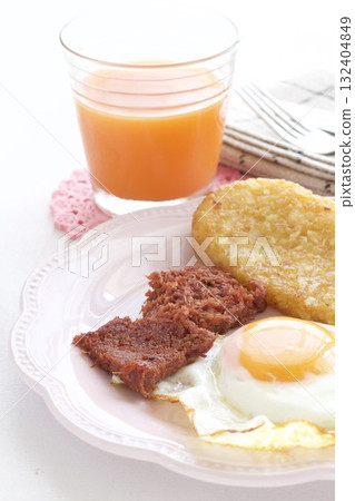 A breakfast plate of fried eggs, hash browns, corned beef, and carrot juice A breakfast plate of fried eggs, hash browns, corned beef, and carrot juice 132404849