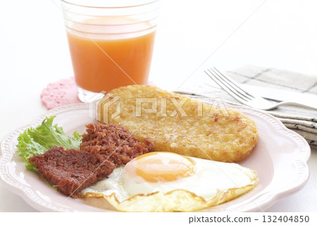 A breakfast plate of fried eggs, hash browns, corned beef, and carrot juice A breakfast plate of fried eggs, hash browns, corned beef, and carrot juice 132404850