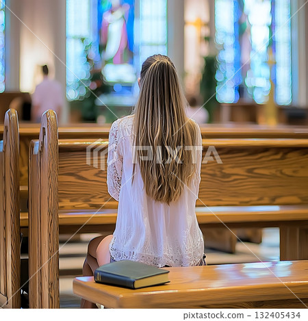 Woman sits in a church pew with a book in front of her Woman sits in a church pew with a book in front of her 132405434
