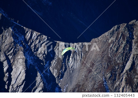Paragliders flying over rocky ridges Paragliders flying over rocky ridges 132405443