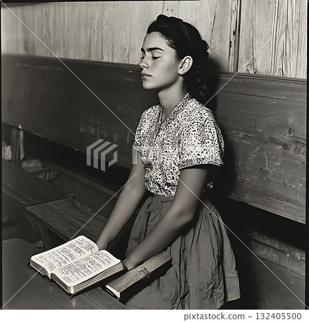 Young woman sits in a classroom with her hands on her knees 132405500