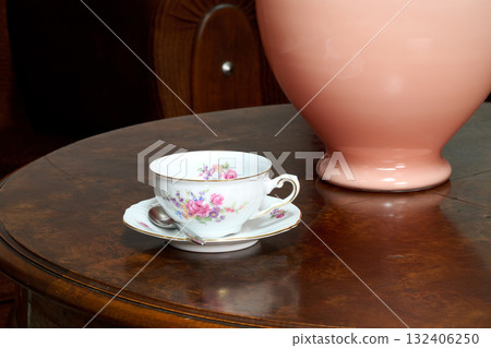 teacup and vase on round wooden table teacup and vase on round wooden table 132406250