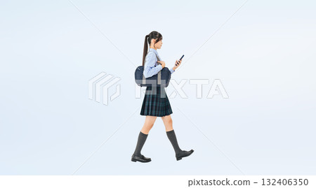 Full-body photo of a female student in uniform walking while looking at her smartphone Full-body photo of a female student in uniform walking while looking at her smartphone 132406350