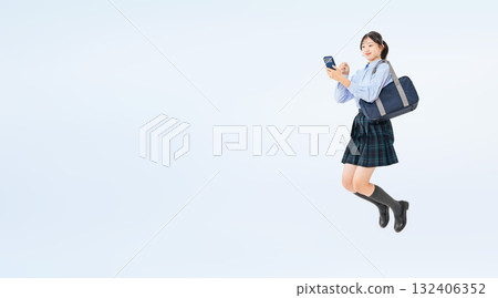 身穿制服的女學生拿著智慧型手機跳躍的全身照片 132406352