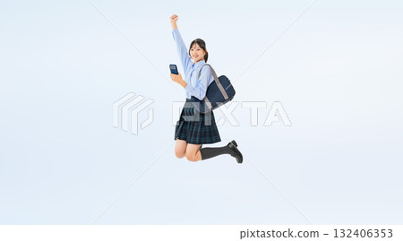 Full-body photo of a female student in uniform jumping with a smartphone Full-body photo of a female student in uniform jumping with a smartphone 132406353