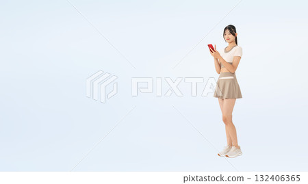 Full-body photo of a woman in sportswear using a smartphone 132406365
