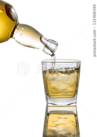 Pouring Whiskey from a bottle into a glass with ice on a white background. Pouring Whiskey from a bottle into a glass with ice on a white background. 132406399