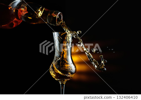 Rum being poured from a bottle into a glass. 132406410