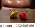 red and yellow spinning top on wooden plank 132406466