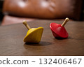 red and yellow spinning top on wooden plank 132406467