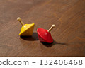 red and yellow spinning top on wooden plank 132406468
