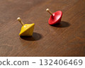 red and yellow spinning top on wooden plank 132406469