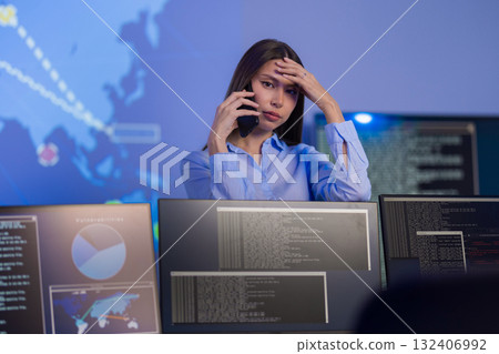Concerned analyst monitoring cybersecurity incidents in SOC environment on multiple screens 132406992