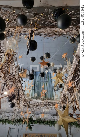 A whimsical ceiling decoration with natural branches, black and white balloons, and sparkling golden stars hanging over a doorway. 132407642