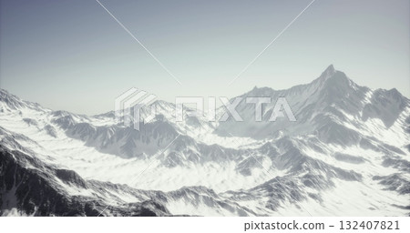 Majestic peaks rise dramatically against a clear sky, blanketed in shimmering snow. The tranquil landscape reveals the stunning beauty of untouched wilderness in the early morning light. 132407821
