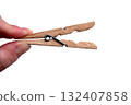 A wooden clothespin in hand isolated. An open clothes peg held in fingers. 132407858