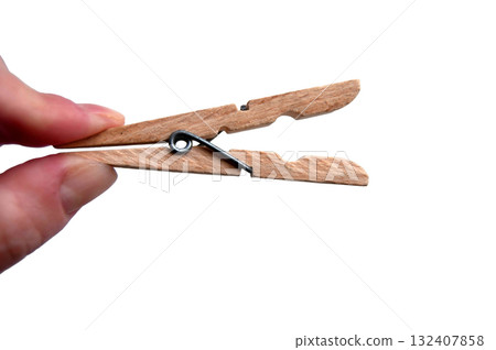 A wooden clothespin in hand isolated. An open clothes peg held in fingers. 132407858