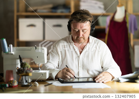 Male tailor create sketch of dress on tablet Male tailor create sketch of dress on tablet 132407905