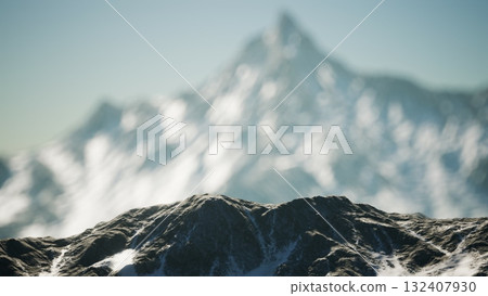 Snow capped peaks rise against a bright sky, showcasing natures grandeur. The rugged mountains, covered in white, evoke a sense of tranquility and awe, beckoning adventure seekers. 132407930