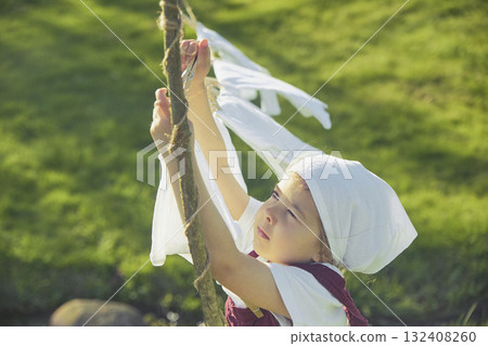 Charming girl washing clothes in the garden. Retro portrait 132408260
