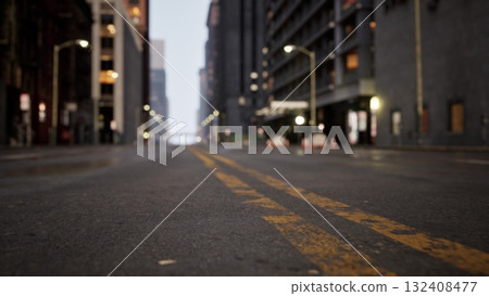 Early morning reveals a deserted street in an urban area. The soft glow from streetlights reflects on the damp pavement, creating a tranquil atmosphere in a bustling city. Early morning reveals a deserted street in an urban area. The soft glow from streetlights reflects on the damp pavement, creating a tranquil atmosphere in a bustling city. 132408477