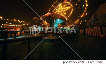 The amusement park remains silent at night, featuring brightly lit rides and stalls, showcasing a vibrant but unoccupied atmosphere as colorful lights illuminate the dark surroundings. The amusement park remains silent at night, featuring brightly lit rides and stalls, showcasing a vibrant but unoccupied atmosphere as colorful lights illuminate the dark surroundings. 132408508