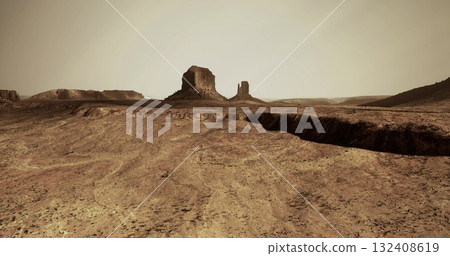 A vast desert terrain features rugged rock formations against a muted, hazy sky. The dry environment highlights the arid conditions and geological features present in the area. 132408619