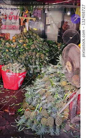Large piles of fresh, harvested pineapples at a busy, local, outdoor market stall ready for sale in Thailand. Large piles of fresh, harvested pineapples at a busy, local, outdoor market stall ready for sale in Thailand. 132408727