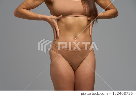 Fit woman touching waist showing mild abdominal tension and self-body care Fit woman touching waist showing mild abdominal tension and self-body care 132408736