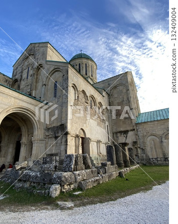 Ancient stone cathedral with arched entrance and cloudy blue sky background 132409004