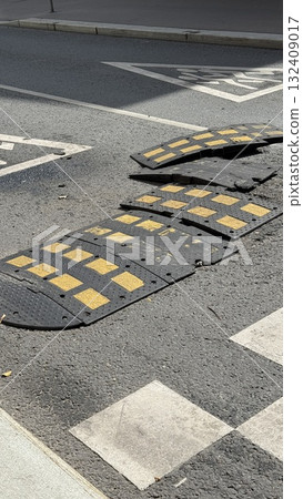 Damaged speed bump on asphalt road with yellow markings for traffic safety background 132409017