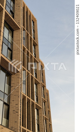 Modern brick building facade against clear blue sky, vertical architectural background 132409021