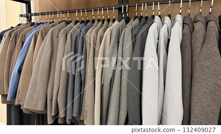 Row of neatly arranged business suits in various shades hanging on clothing rack background 132409027