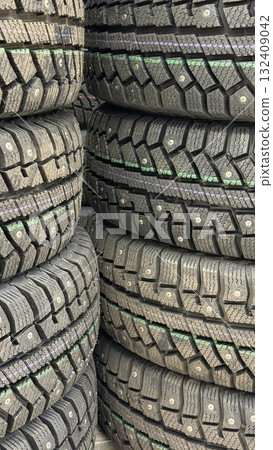 Stacks of winter tires with studded treads arranged vertically in industrial setting 132409042