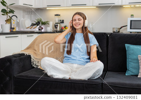 Young woman relaxes with wireless headphones listens to favorite music rests eyes calm and peaceful 132409081