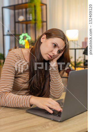 Young woman sits at laptop leans on hand looks so sad unmotivated to continue work emotional burnout Young woman sits at laptop leans on hand looks so sad unmotivated to continue work emotional burnout 132409120