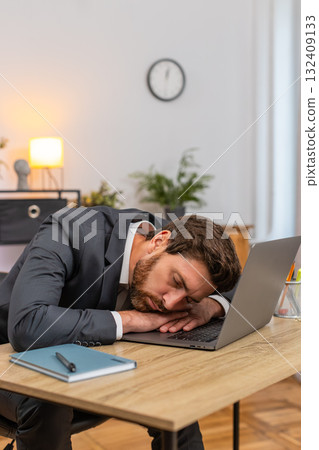 Middle-aged businessman exhausted types report falls asleep on laptop keyboard face down during work 132409133