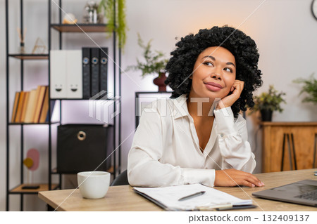 African American businesswoman daydreams resting chin on hand gazes away thinking about future plans African American businesswoman daydreams resting chin on hand gazes away thinking about future plans 132409137