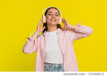 Woman dancing with closed eyes listening to music in headphones expressing carefree joyful emotion 132409211