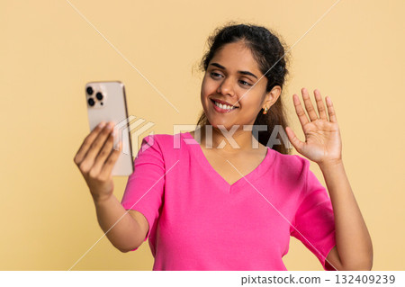 Indian woman energetically waving, filming herself talking and smiling, recording engaging video 132409239