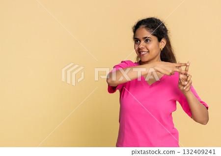 Indian woman gesturing hashtag symbol with fingers, playfully suggesting social media topic 132409241