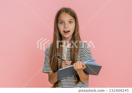 Child girl kid thoughtfully writing notes in notebook diary carefully planning detailed to-do list 132409245