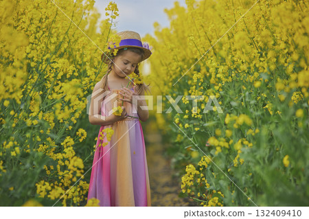 charming child in sundress in a rapeseed field charming child in sundress in a rapeseed field 132409410