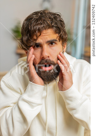 Portrait of upset Indian young man making face, disappointed in result, bad news sitting on sofa 132409742