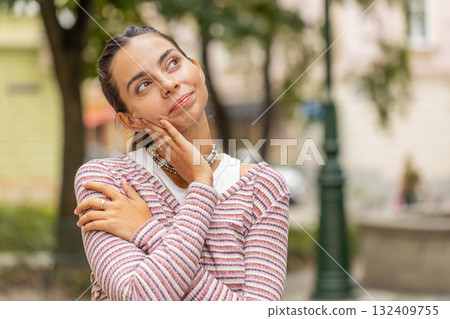 Thoughtful smiling happy young woman with pensive expression pondering a solution dreaming thinking 132409755