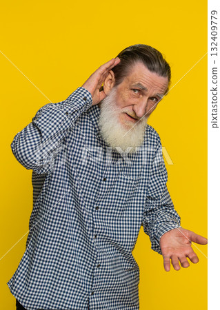 Senior old man trying hear you looking confused and frowning keeping arm near ear for louder voice Senior old man trying hear you looking confused and frowning keeping arm near ear for louder voice 132409779