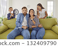Tired mother and father sitting on couch at home while noisy kids shouting in loudspeaker. 132409790
