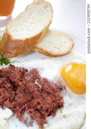 Breakfast: fried eggs, corned beef, and French bread Breakfast: fried eggs, corned beef, and French bread 132409794